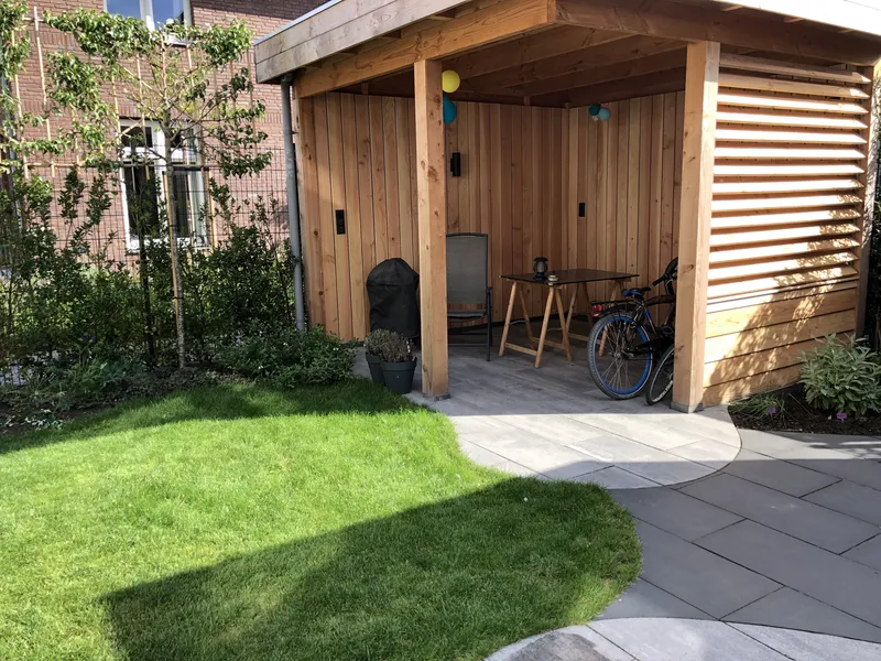 Tuin met glooiende lijnen en overkapping, gezien vanaf de zijkant
