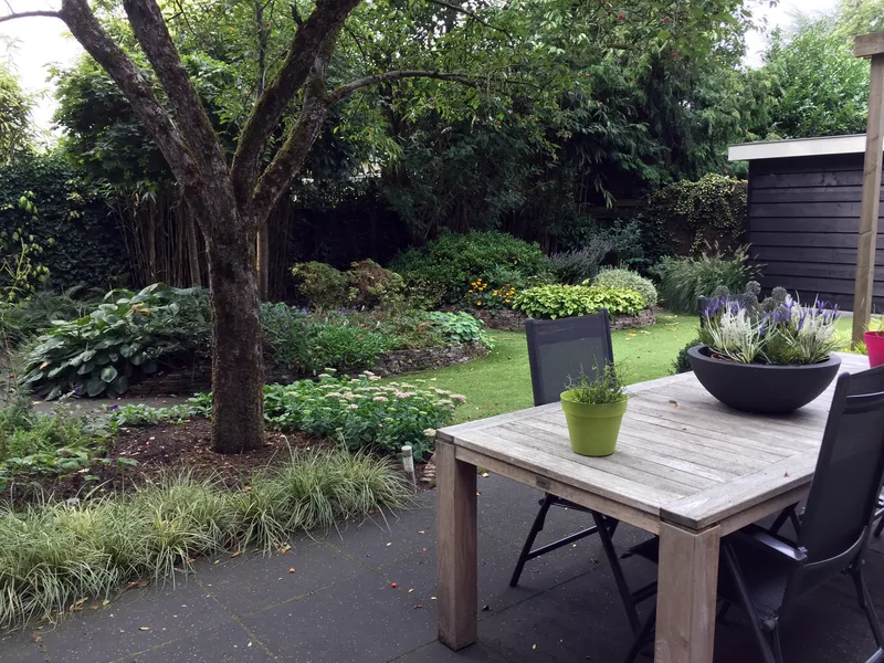 Tuinaanleg met overkapping en groene beplanting